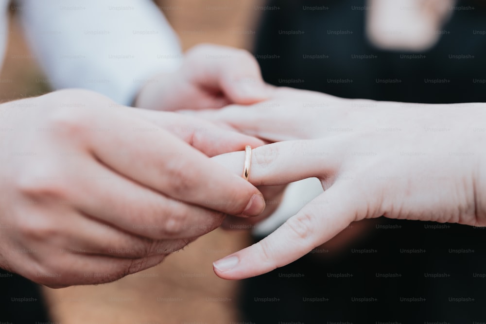 Un primer plano de una persona poniendo un anillo de bodas en el dedo de otra persona