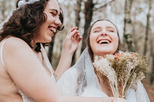 two brides laughing together in the woods
