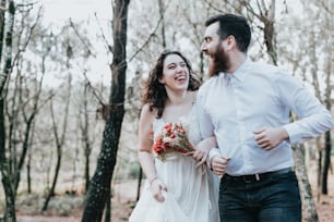 a bride and groom laughing in the woods