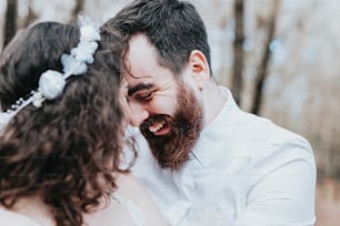 a bride and groom laughing together in the woods