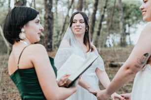 Una mujer con un vestido de novia cogida de la mano con otra mujer