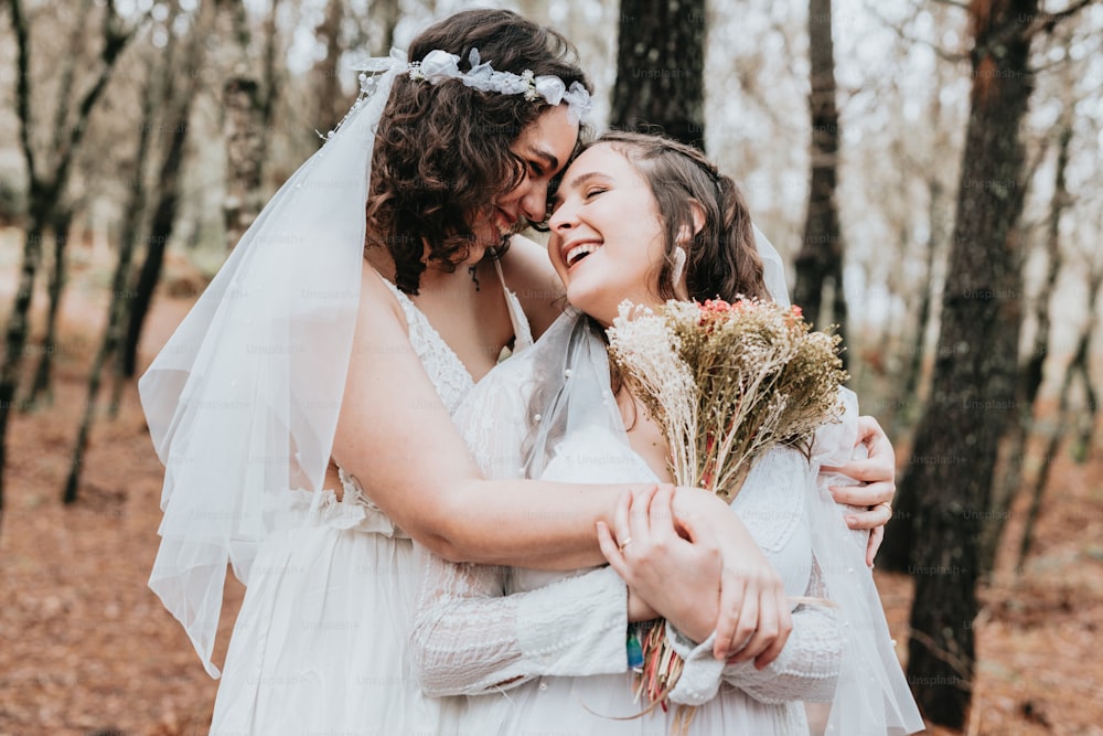 two brides hugging each other in the woods