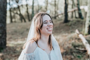 a woman in a white wedding dress standing in the woods