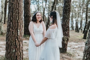 Dos novias de pie en el bosque tomadas de la mano