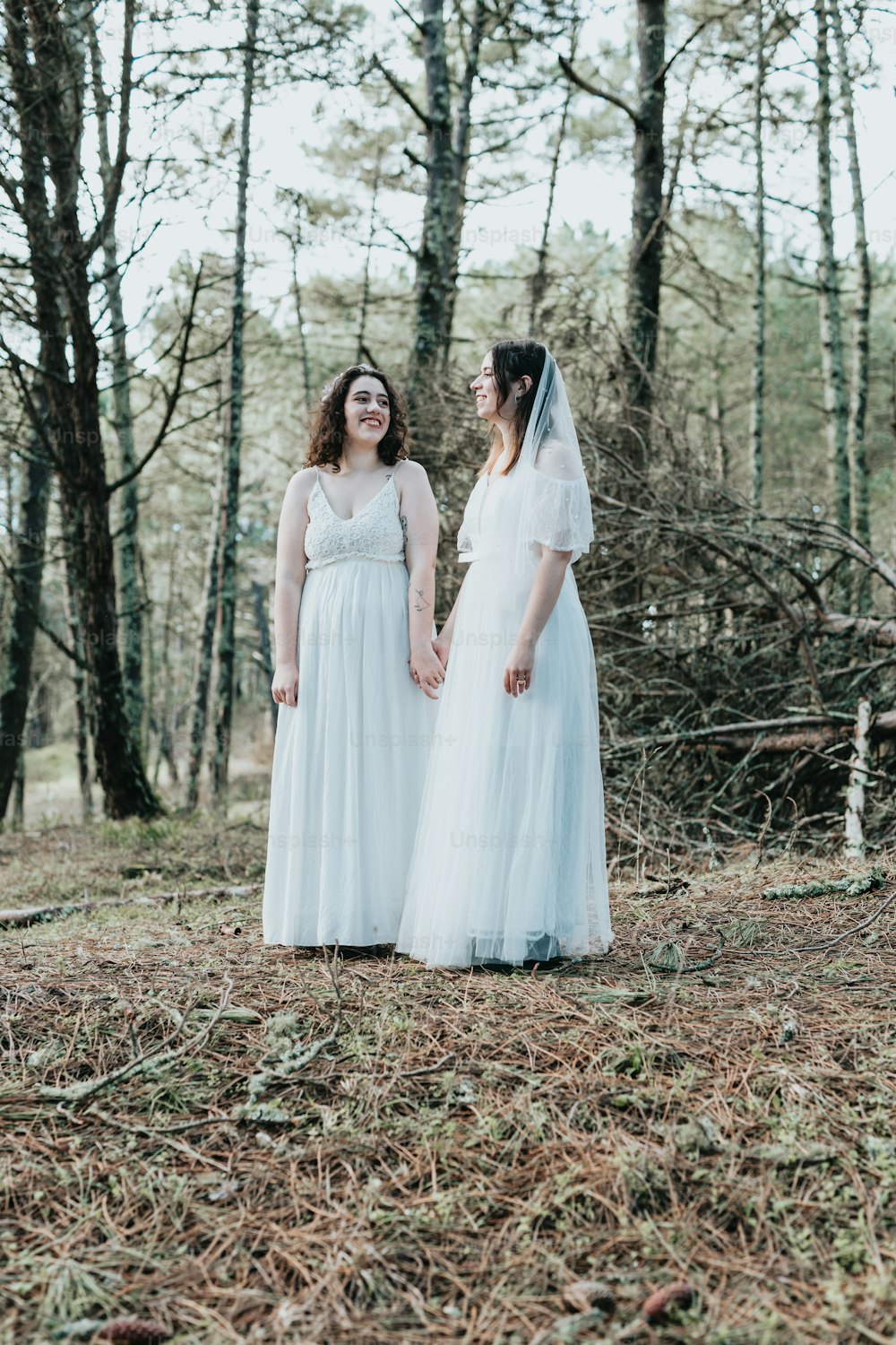 two women standing in the woods holding hands
