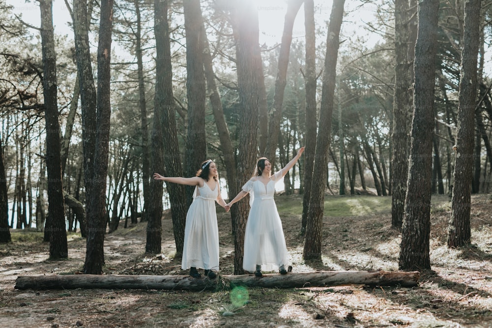 two women standing on a log in the woods