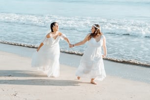 a couple of women walking on top of a sandy beach