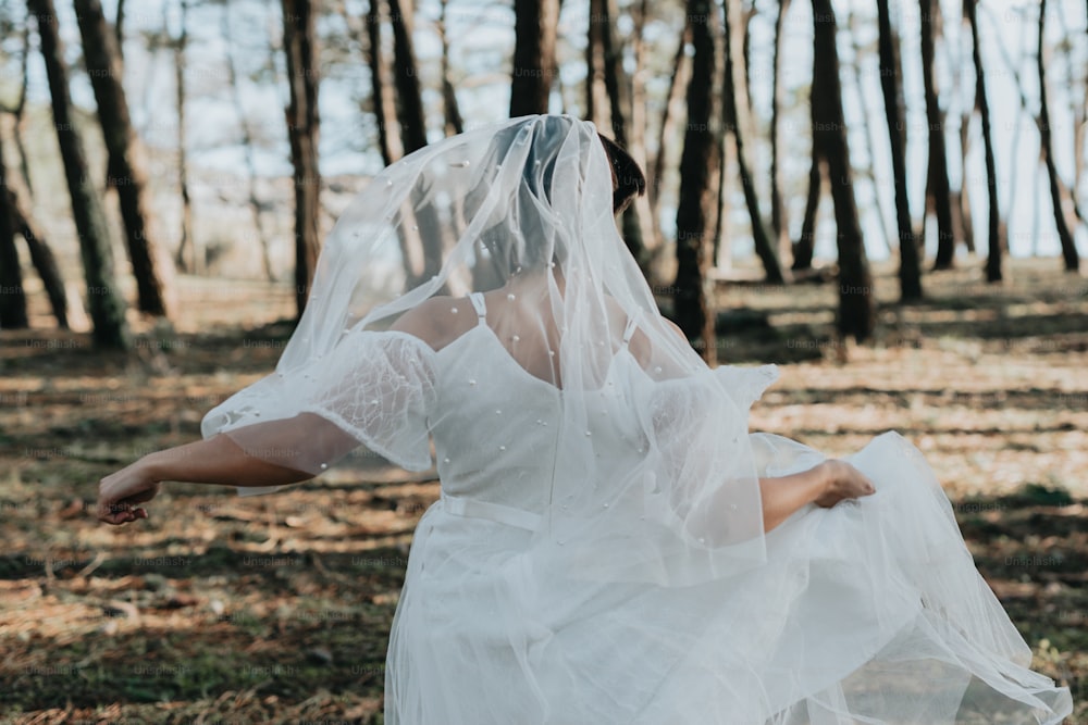 Eine Frau im weißen Kleid geht durch den Wald