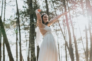 Una mujer con un vestido blanco parada en el bosque