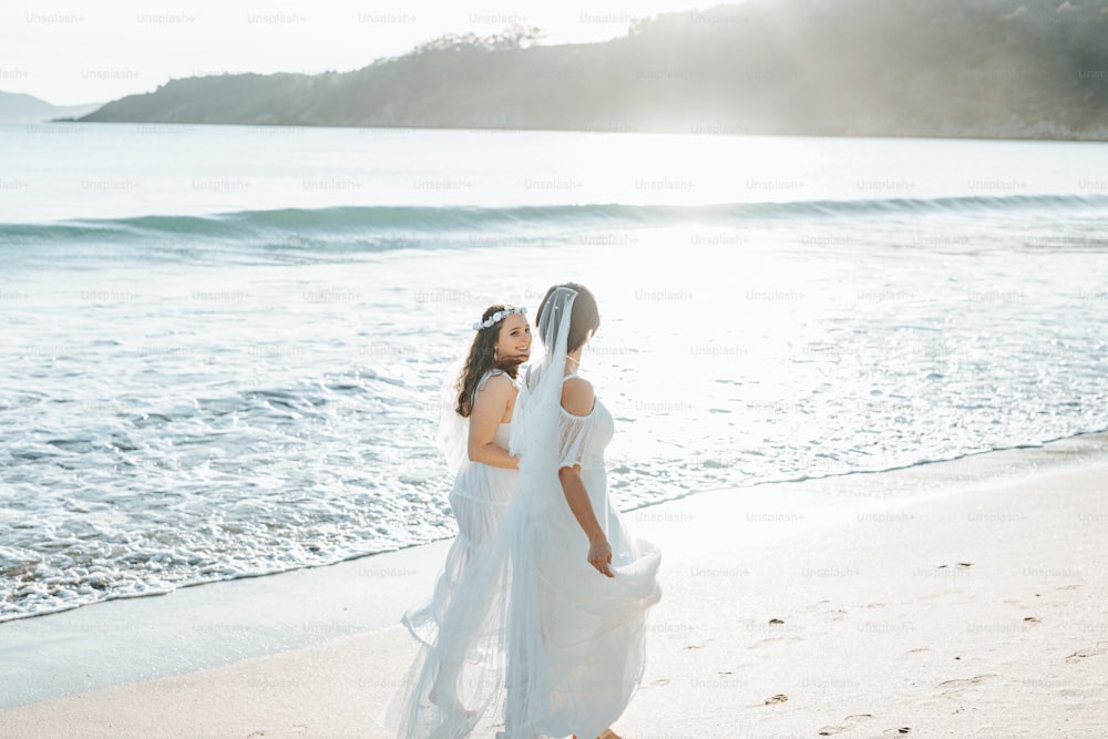 um casal de mulheres em pé no topo de uma praia