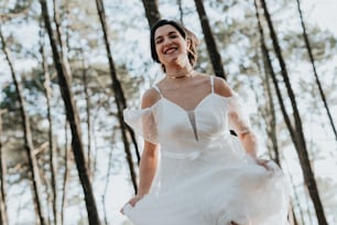 a woman in a white dress is walking through the woods