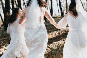 a couple of women in white dresses walking through a forest