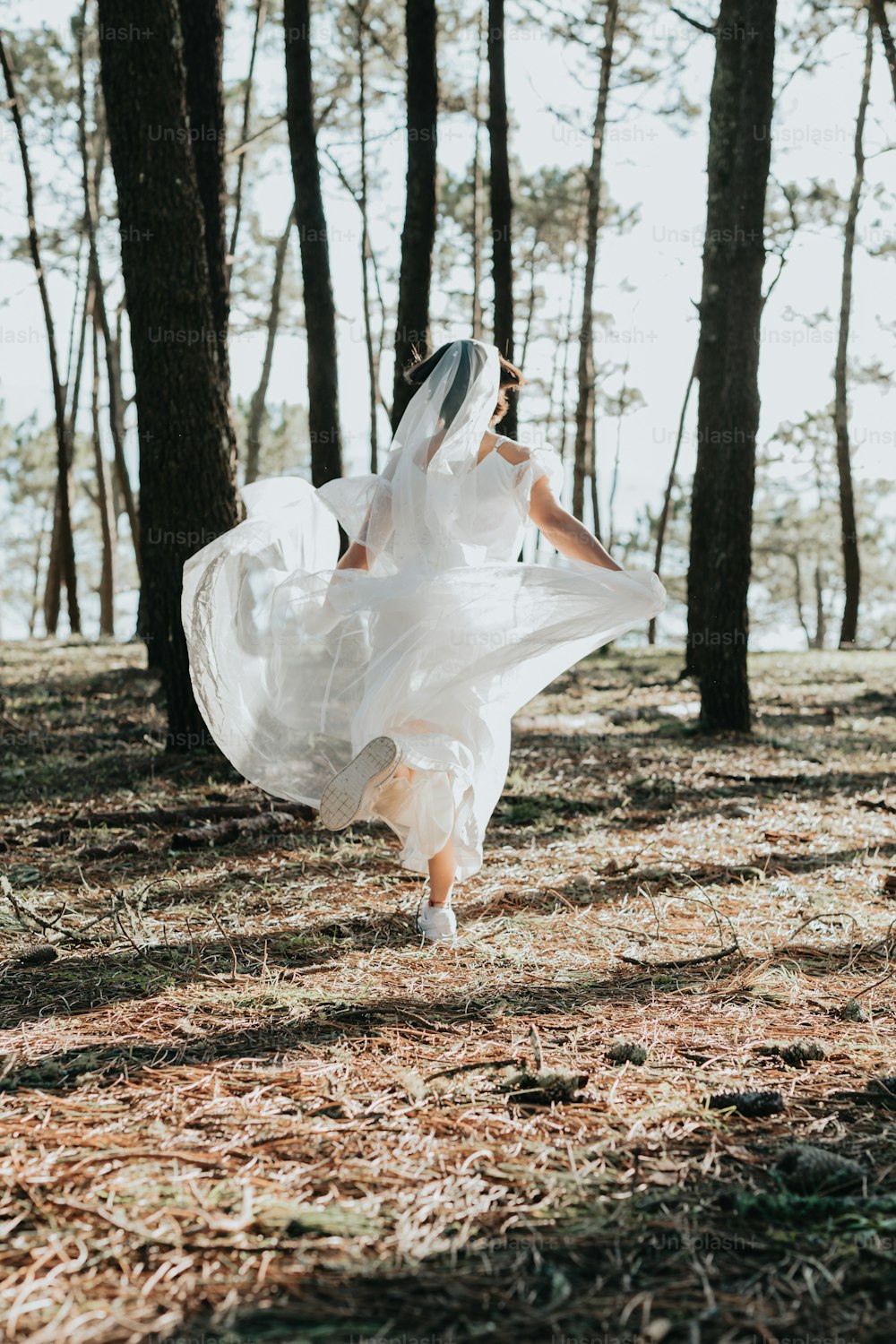 白いドレスを着た女性が森の中を走っている