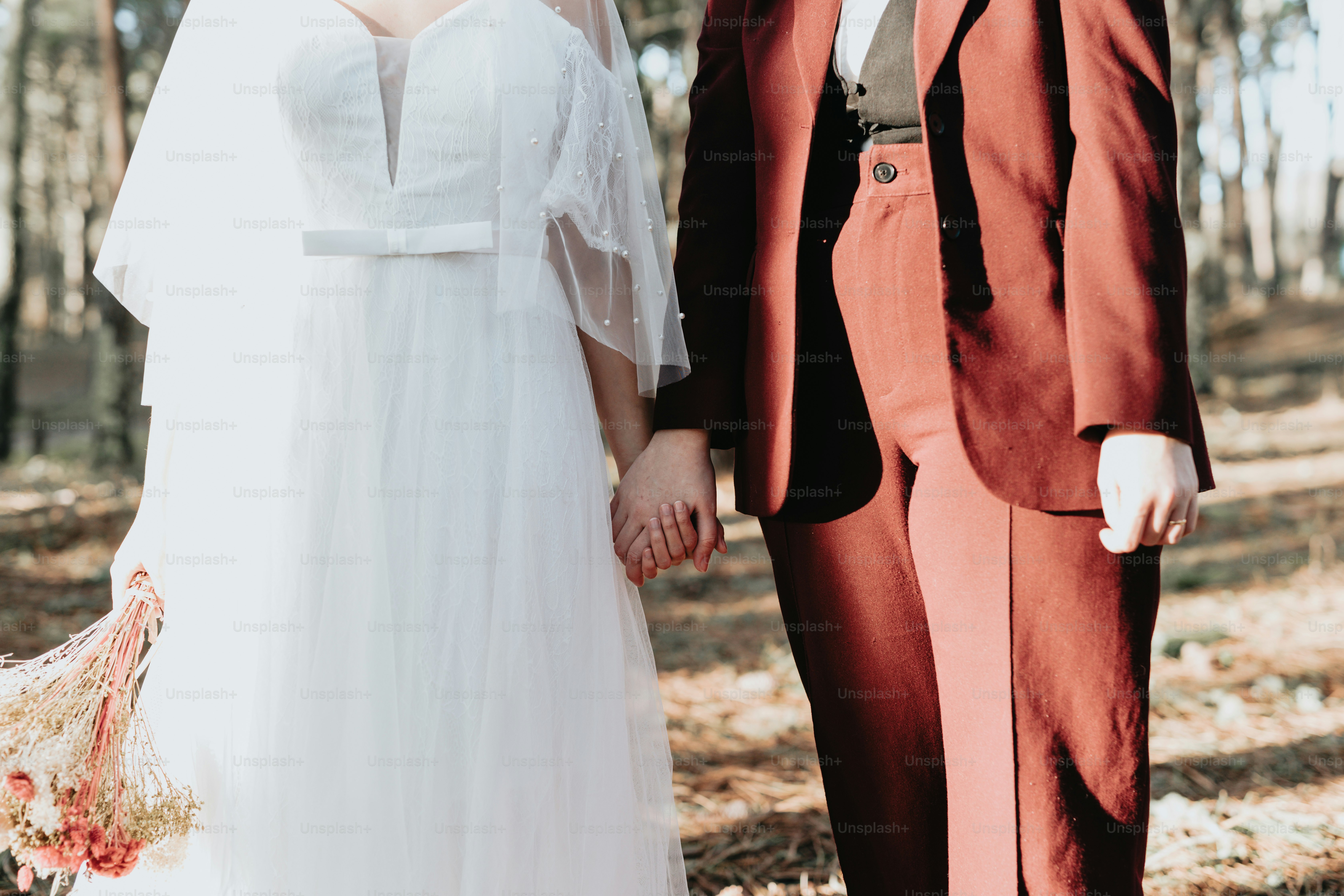 A bride and groom holding hands in the woods photo – Wedding day Image ...