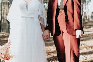 a bride and groom holding hands in the woods