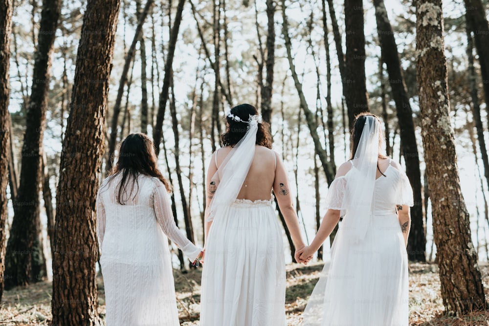 three brides holding hands in the woods