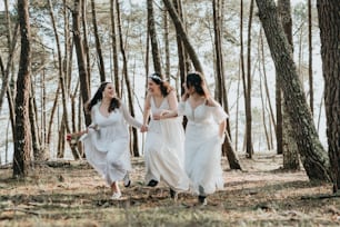 three women in white dresses walking through the woods