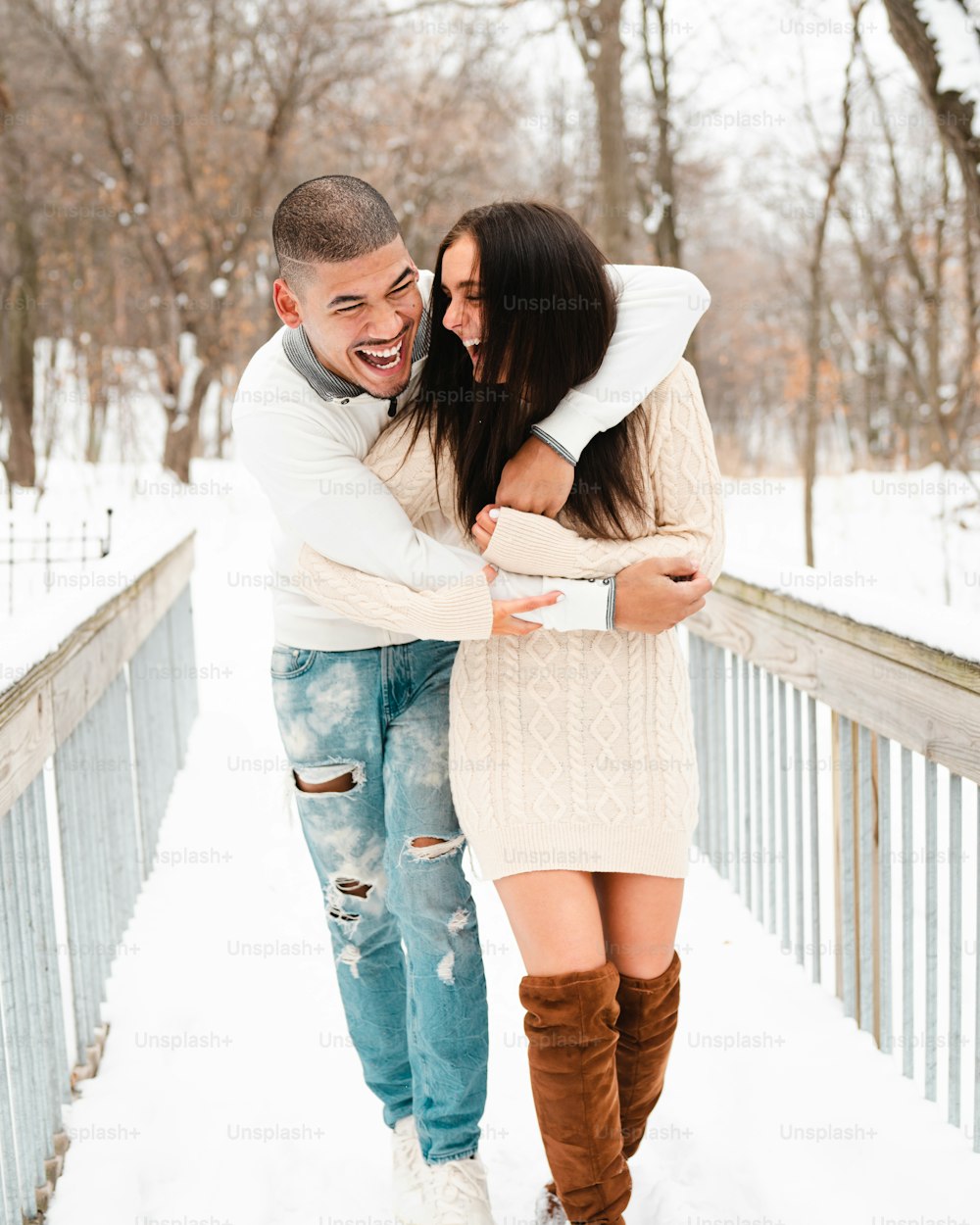 um homem e uma mulher de pé em uma ponte na neve