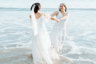 Dos mujeres con vestidos blancos de pie en el agua
