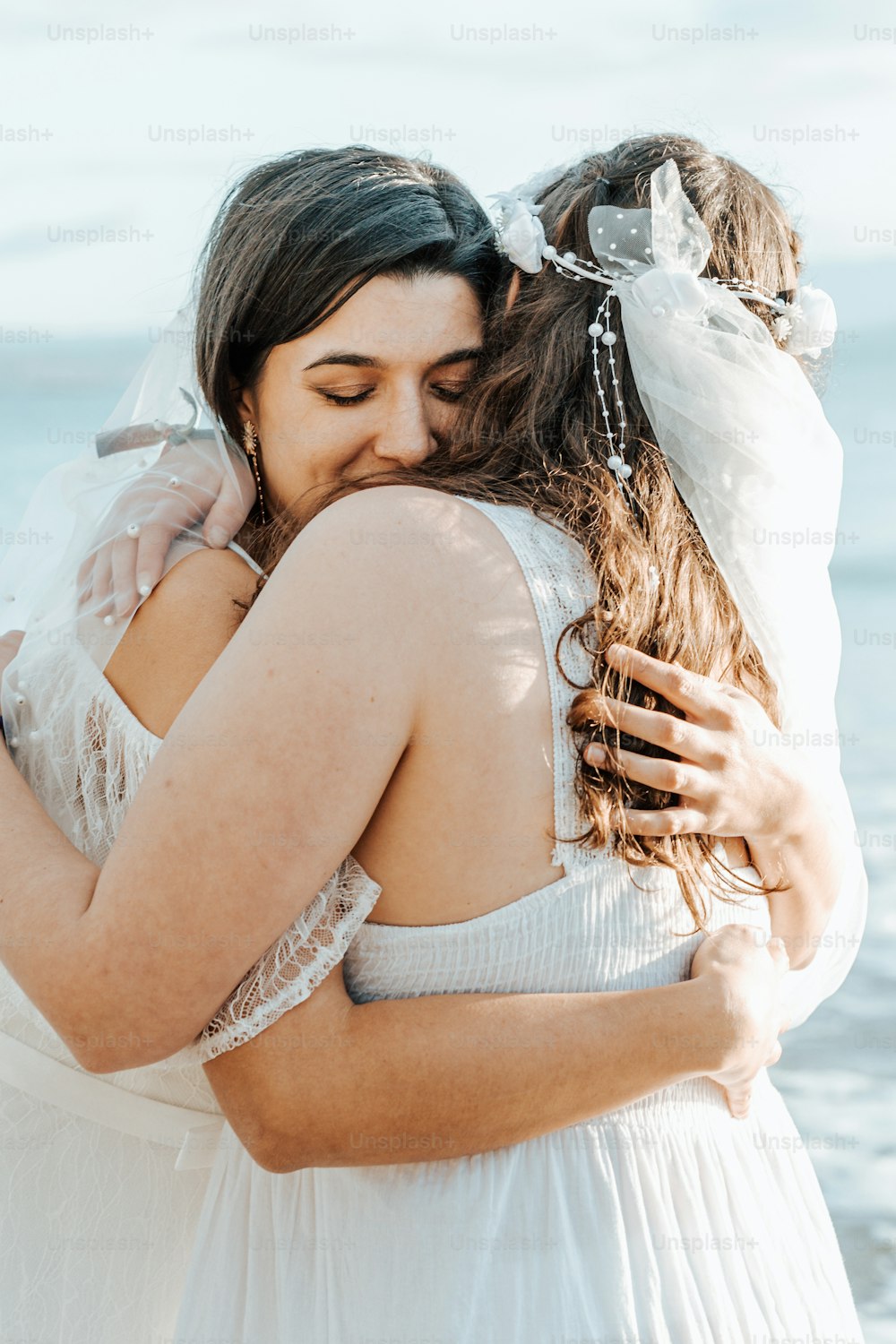 two women hugging each other on the beach