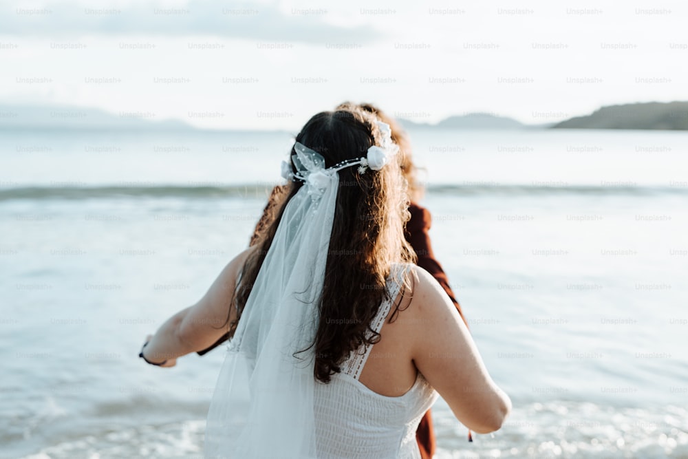 uma mulher em um vestido de noiva que anda na praia