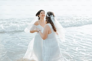 a bride and her maid standing in the water at the beach