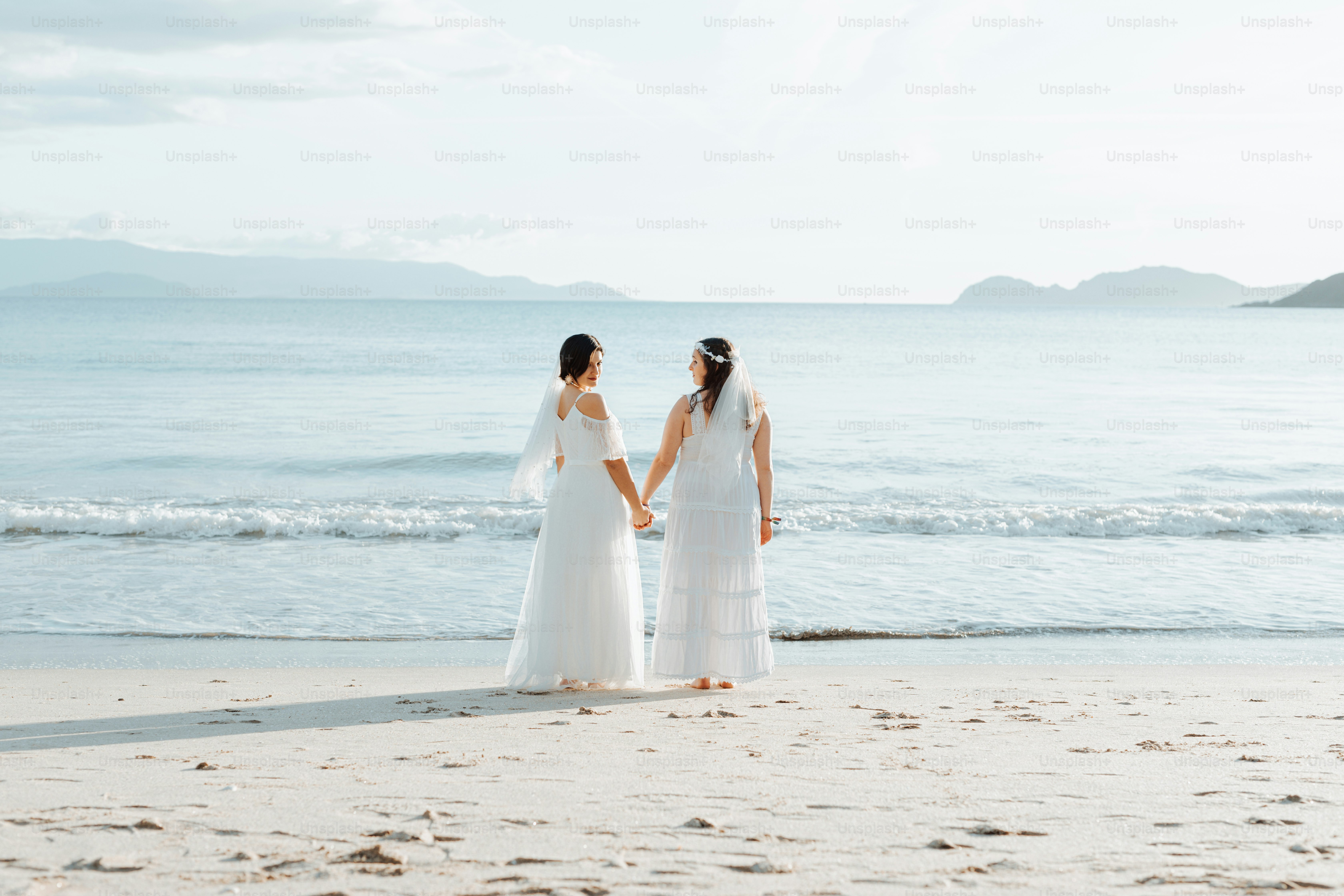 a couple of women standing on top of a sandy beach
