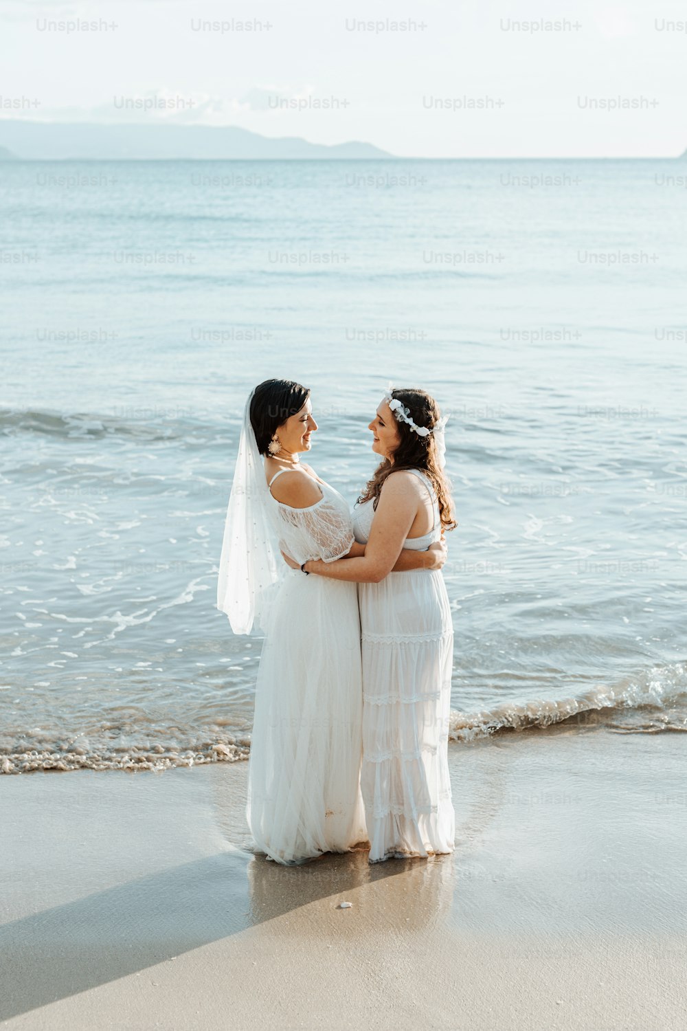 um casal de mulheres de pé um ao lado do outro em uma praia