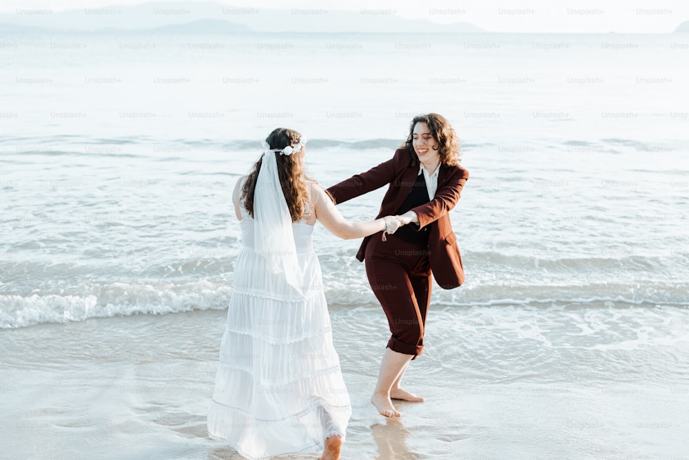a bride and her mother holding hands on the beach