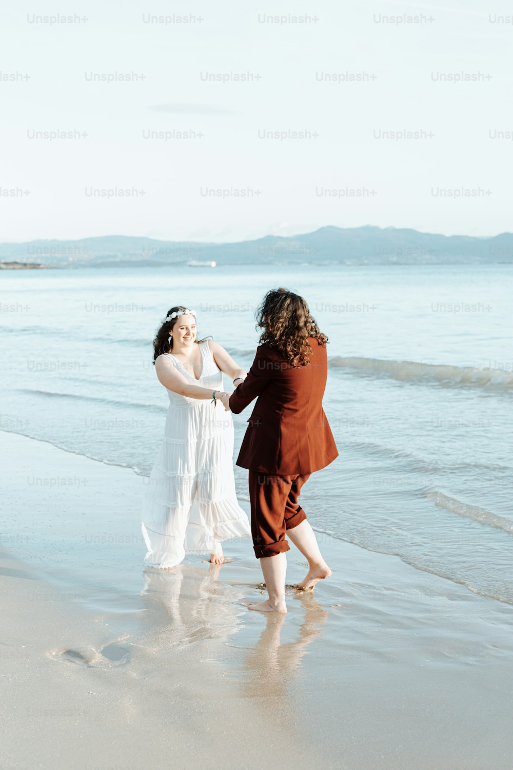 um casal de mulheres em pé no topo de uma praia