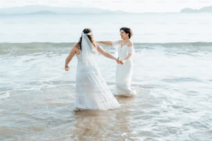 a couple of women standing in the ocean holding hands