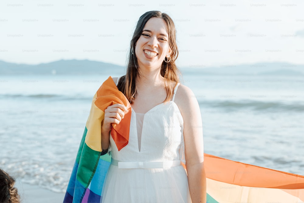 uma mulher em um vestido branco segurando uma bandeira do arco-íris