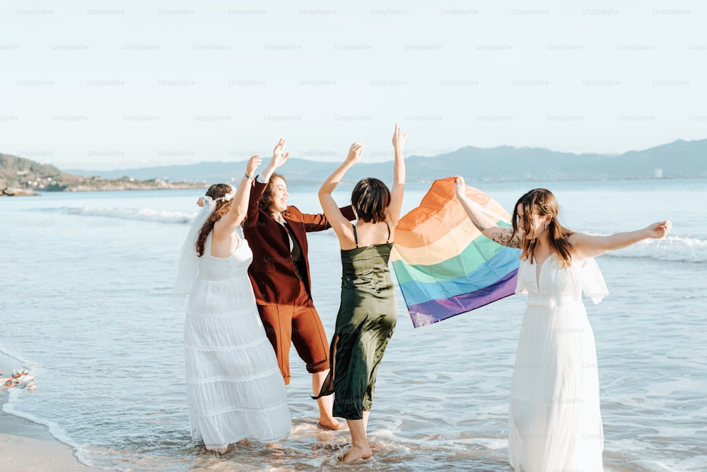 a group of women standing on top of a beach next to the ocean