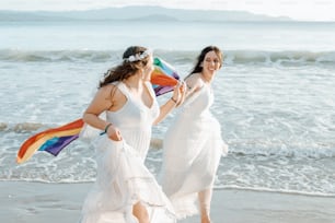 two women in white dresses walking on the beach