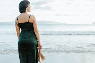 Eine Frau, die an einem Strand steht und auf den Ozean blickt