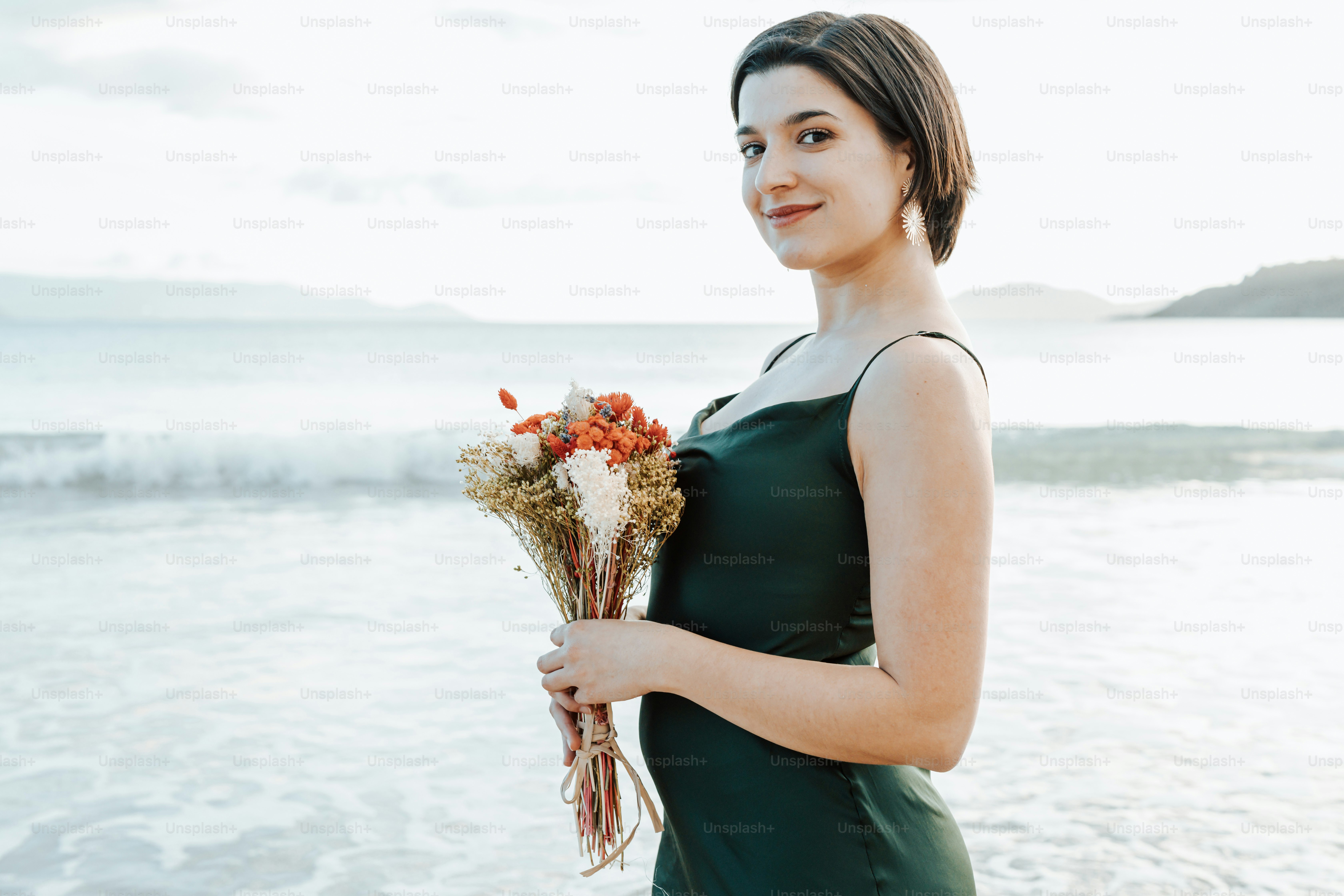A woman in a green dress holding a bouquet of flowers photo – Sea Image ...