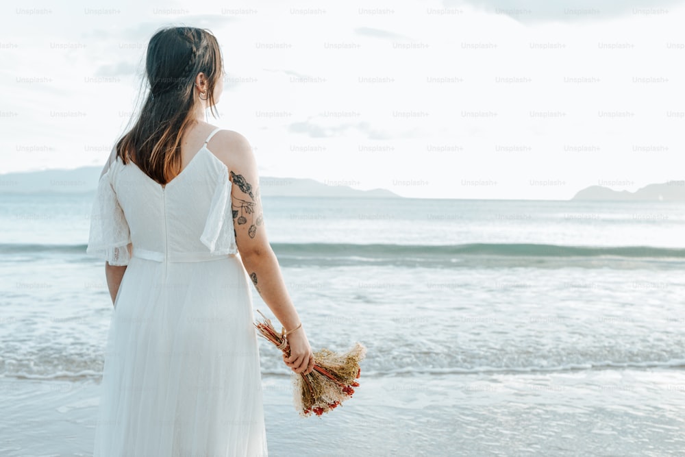 Eine Frau im weißen Kleid steht am Strand