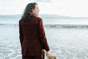 Eine Frau im roten Anzug steht am Strand