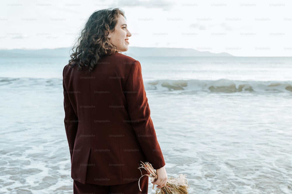 a woman in a red suit standing on the beach