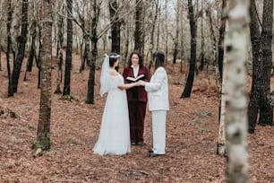 Una sposa e uno sposo in piedi nel bosco durante la loro cerimonia nuziale