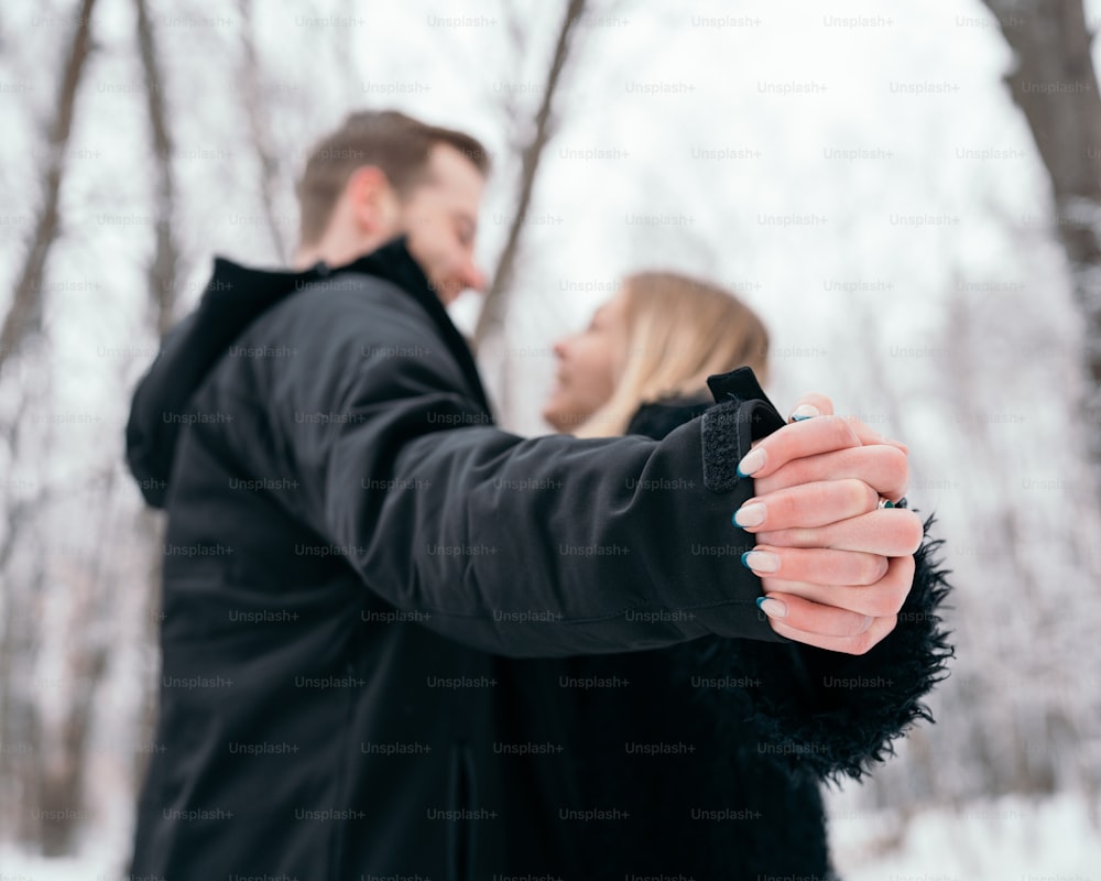 a man and woman holding hands in the snow