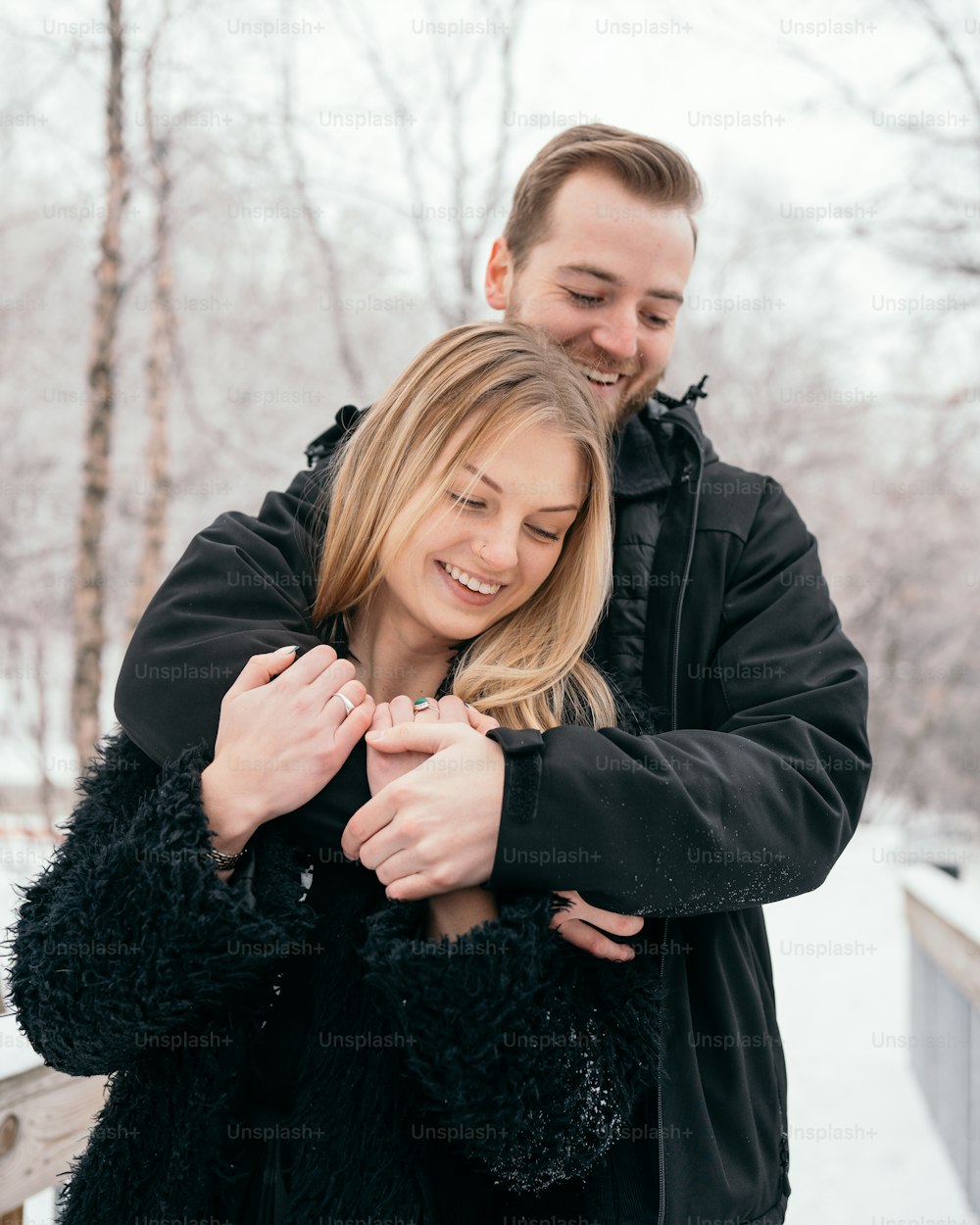 um homem e uma mulher estão se abraçando na neve