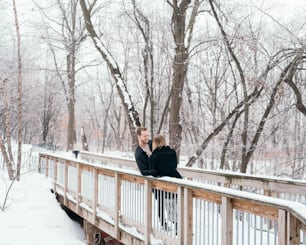 a man and woman standing on a bridge in the snow