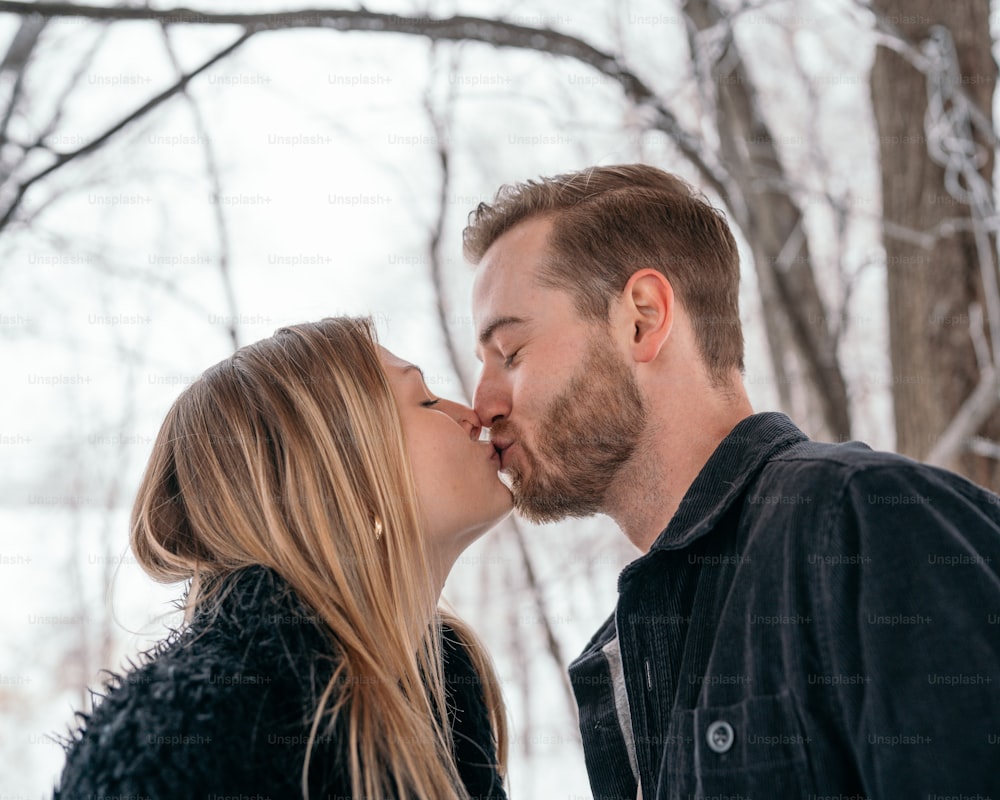 Un homme et une femme s’embrassent dans la neige