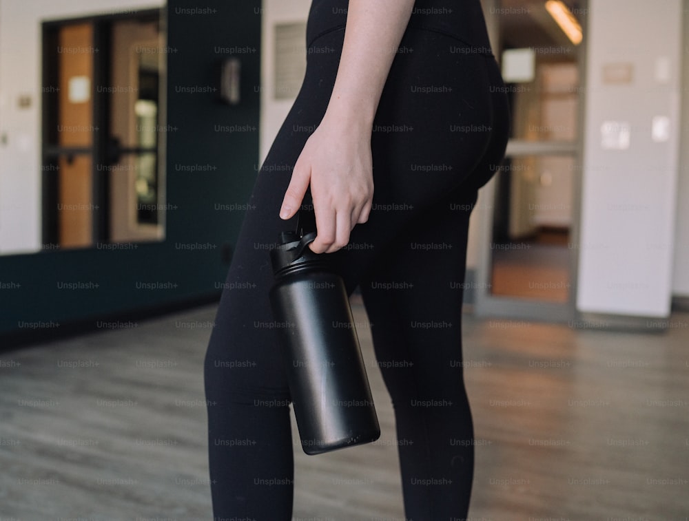 a woman in black pants holding a black cup