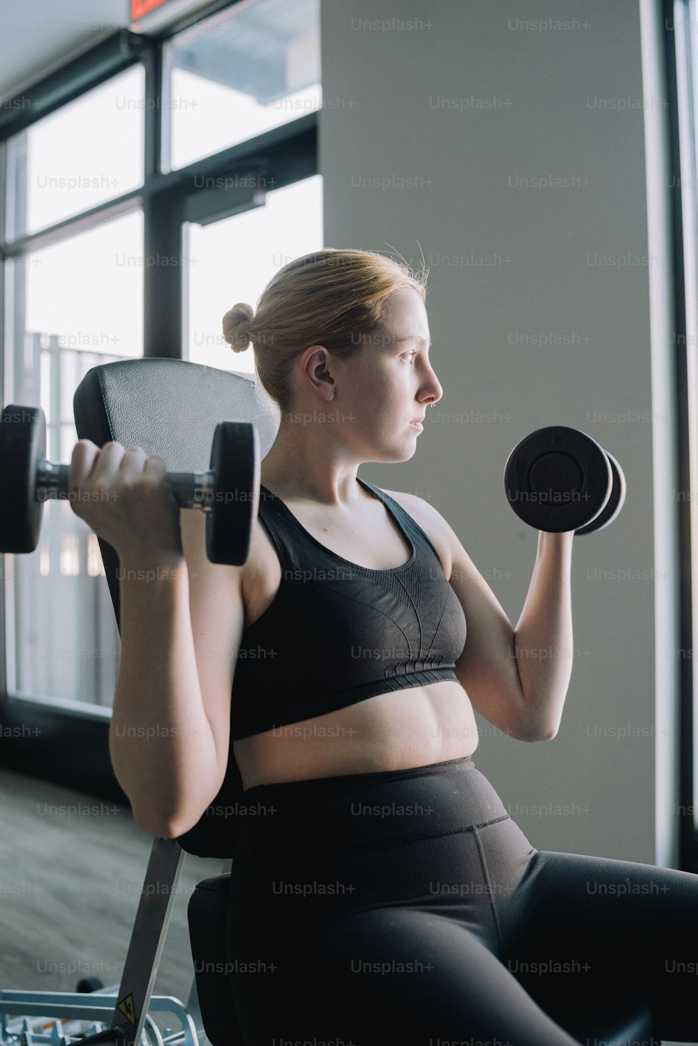 a woman in a sports bra top lifting a dumbbell