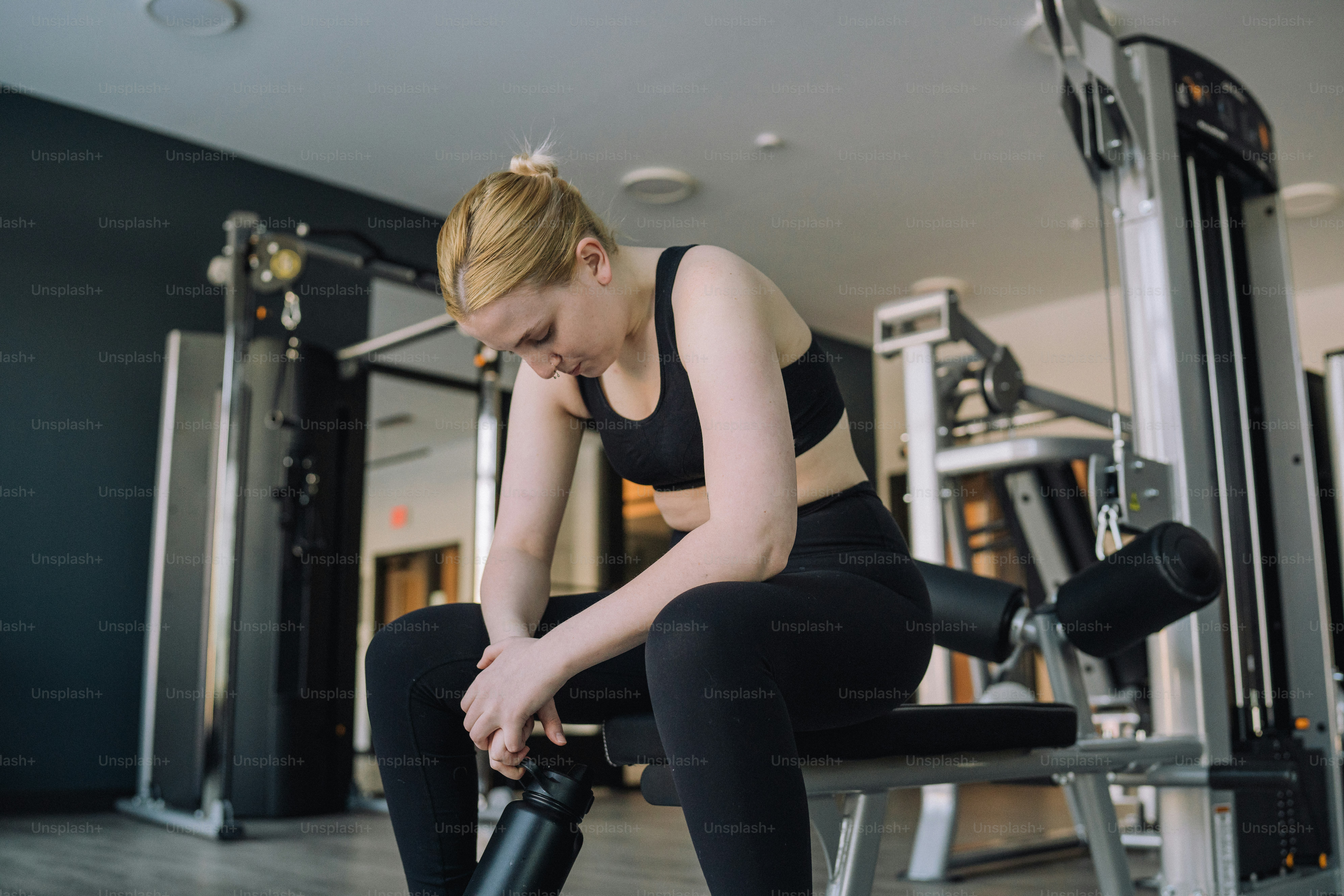 a woman sitting on a bench in a gym