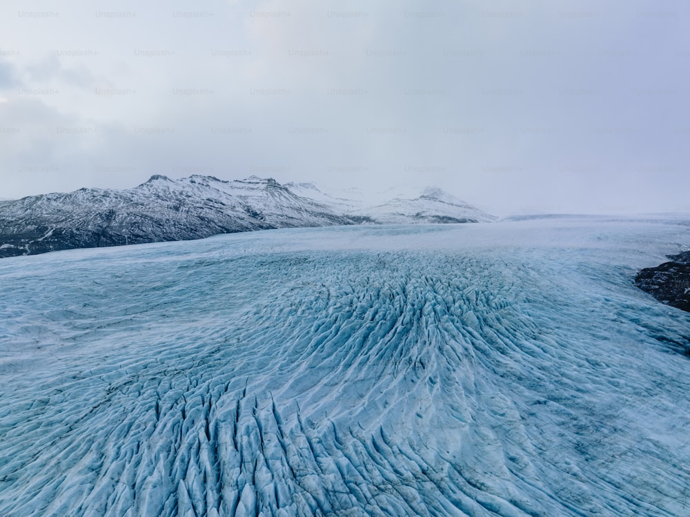 um grande campo de gelo com montanhas ao fundo