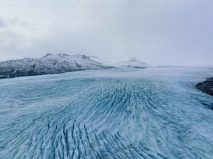 a large ice field with mountains in the background