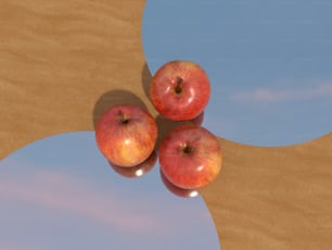 três maçãs sentadas uma em cima da outra em uma mesa